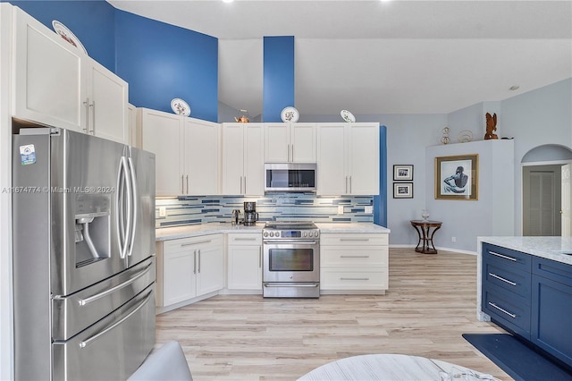 kitchen with appliances with stainless steel finishes, light wood-type flooring, white cabinetry, and backsplash