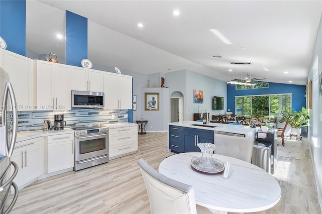 11088 Indian Lake Cir, Boynton Beach, FL 33437 - kitchen featuring appliances with stainless steel finishes, vaulted ceiling, arched walkways, tasteful backsplash, and light countertops