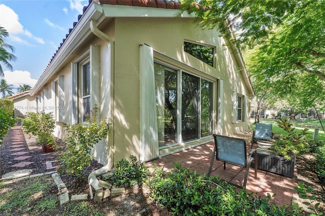 11088 Indian Lake Cir, Boynton Beach, FL 33437 - view of side of property featuring stucco siding, a patio area, and a tile roof
