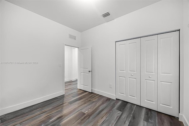 unfurnished bedroom with a closet and dark hardwood / wood-style floors