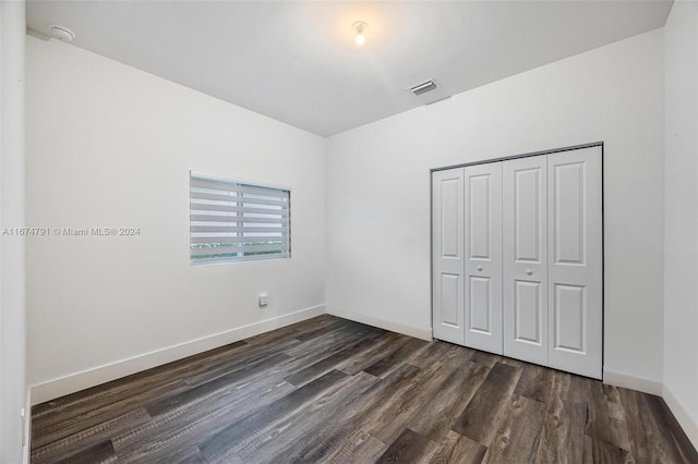 unfurnished bedroom featuring a closet and dark hardwood / wood-style floors