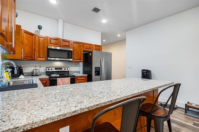 kitchen featuring light stone counters, light hardwood / wood-style floors, sink, and stainless steel appliances