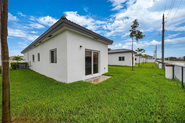 rear view of property featuring cooling unit and a lawn