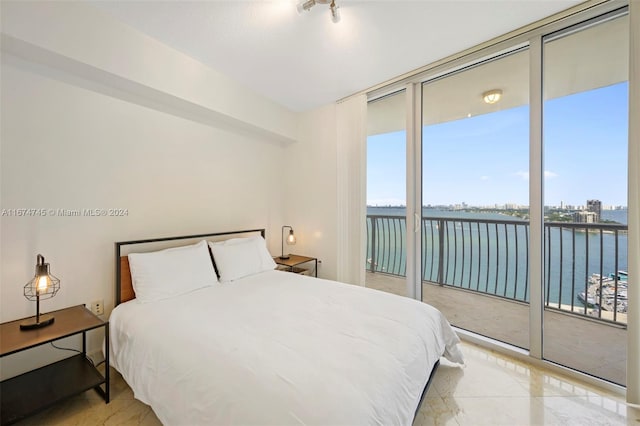 bedroom with expansive windows, a water view, and access to outside