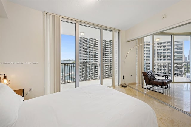 bedroom featuring access to exterior, a water view, and floor to ceiling windows