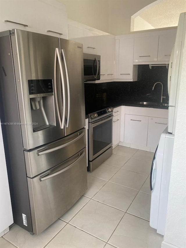 kitchen with appliances with stainless steel finishes, sink, washer / clothes dryer, and white cabinets