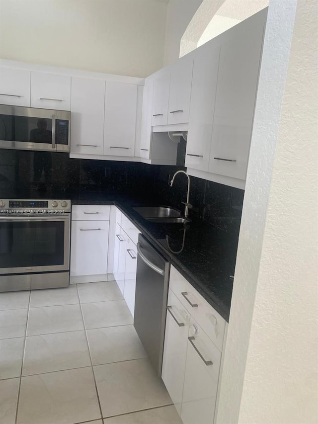 kitchen with white cabinets, light tile patterned flooring, sink, tasteful backsplash, and stainless steel appliances