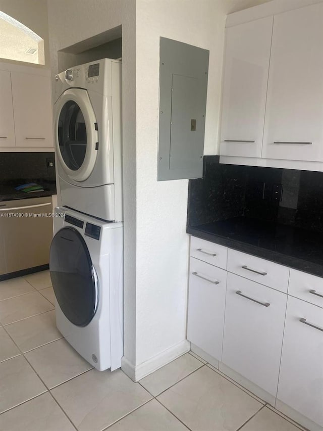 clothes washing area with stacked washer and dryer, electric panel, and light tile patterned flooring