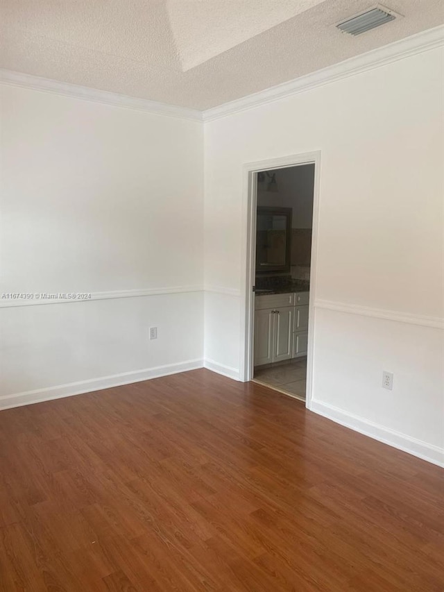 empty room with ornamental molding, a textured ceiling, and dark hardwood / wood-style flooring