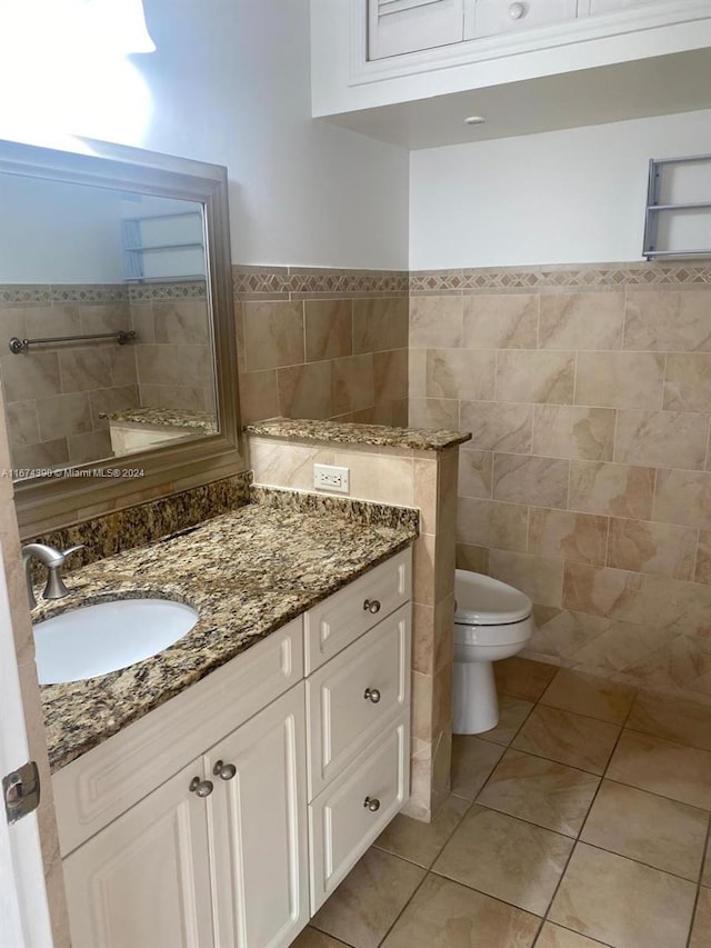 bathroom featuring tile patterned floors, toilet, vanity, and tile walls