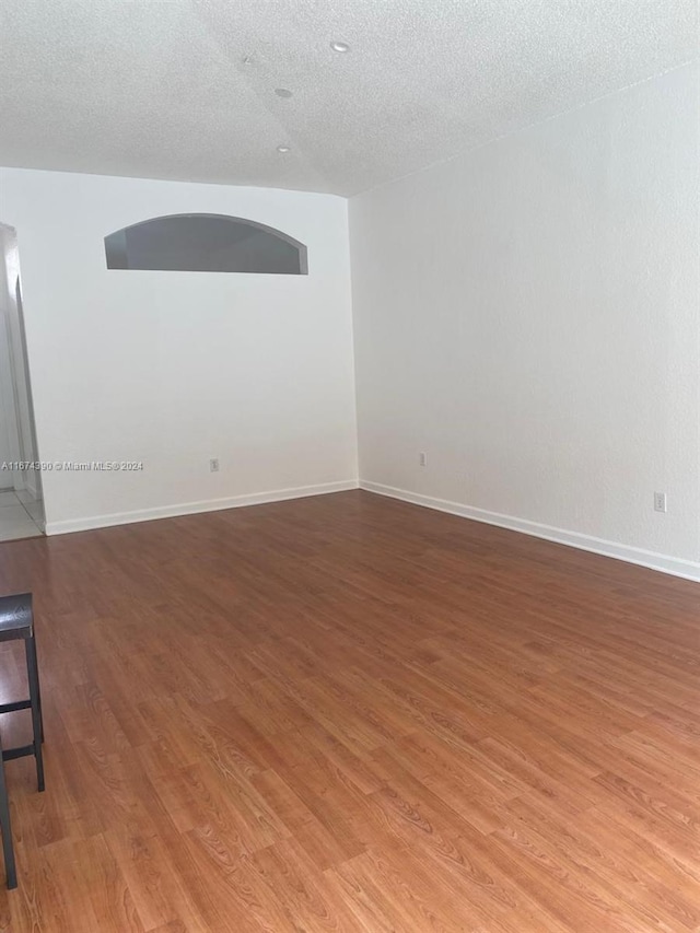 unfurnished room with a textured ceiling and hardwood / wood-style floors