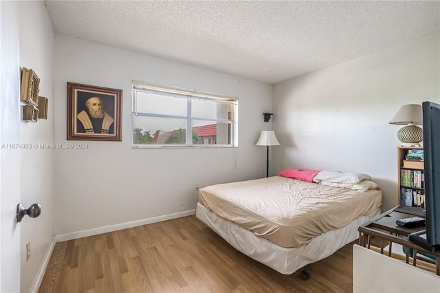 bedroom with a textured ceiling and light hardwood / wood-style flooring