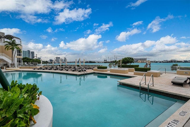 view of swimming pool featuring a water view and a patio area