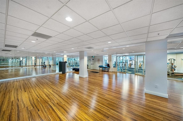 gym featuring a drop ceiling, a wall of windows, and wood-type flooring