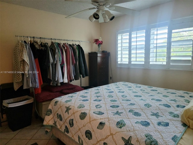 tiled bedroom with ceiling fan and a textured ceiling