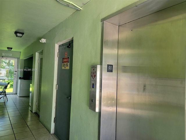 corridor featuring light tile patterned flooring, washer and dryer, and elevator