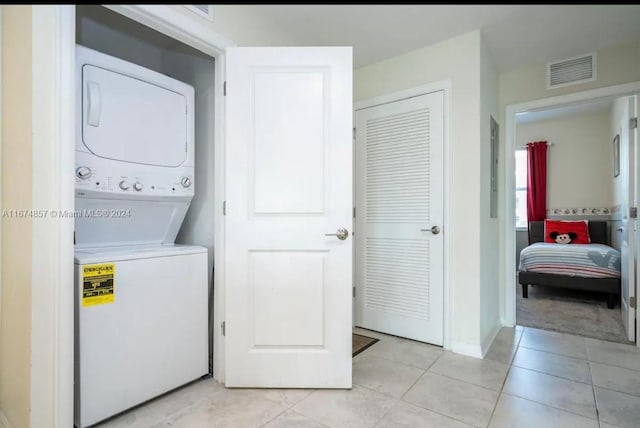 washroom featuring light tile patterned flooring and stacked washer and dryer