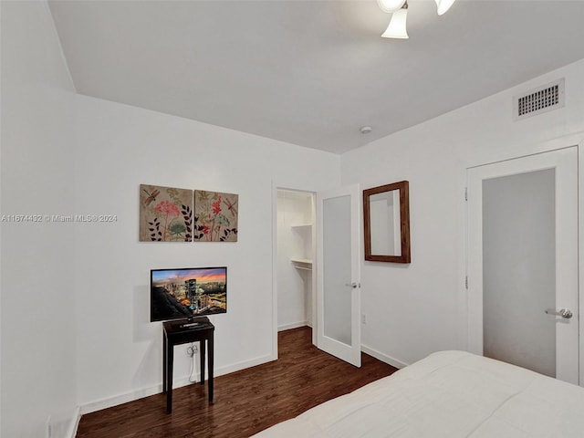 bedroom with a spacious closet, dark hardwood / wood-style floors, a closet, and ceiling fan