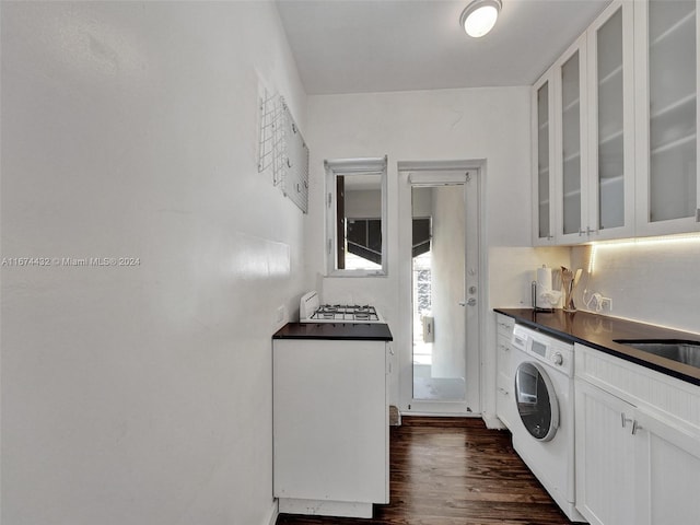 clothes washing area with washer / clothes dryer, sink, and dark wood-type flooring