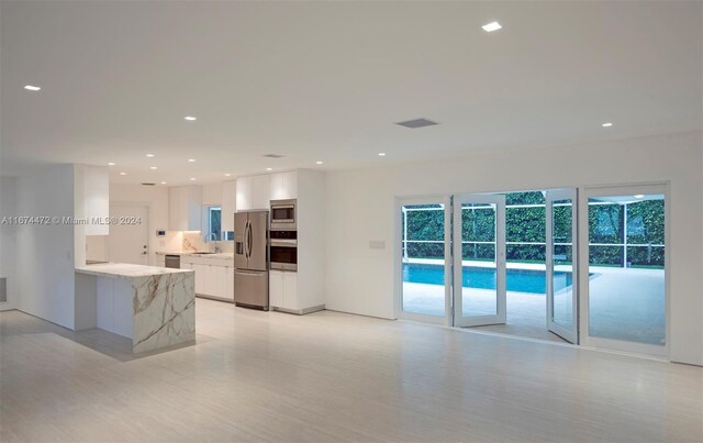 kitchen with white cabinets, sink, light stone countertops, appliances with stainless steel finishes, and kitchen peninsula