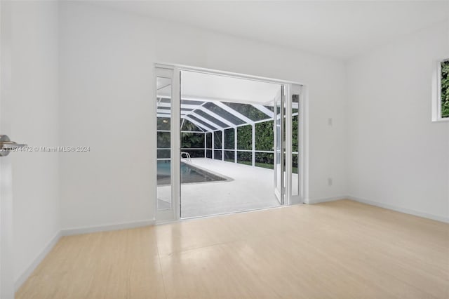 unfurnished room with light hardwood / wood-style floors and lofted ceiling