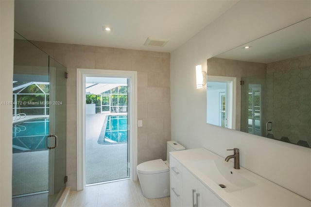 bathroom with an enclosed shower, vanity, toilet, and tile walls