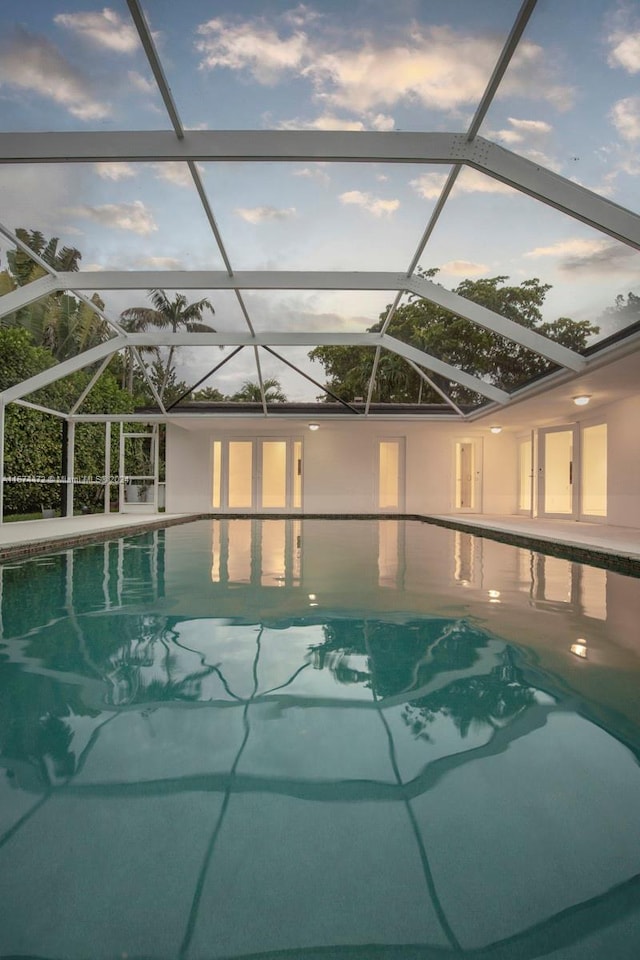 pool at dusk with a patio and a lanai