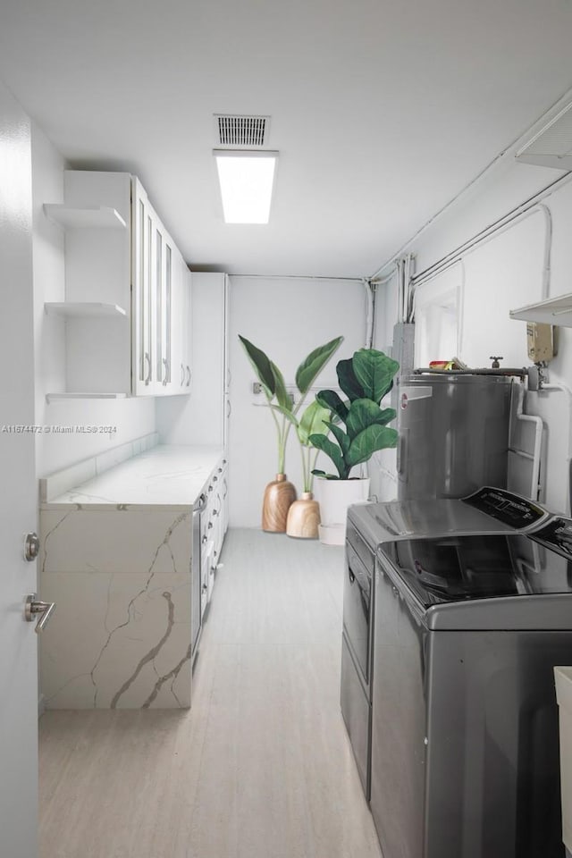 washroom featuring washer and dryer, light hardwood / wood-style floors, and electric water heater