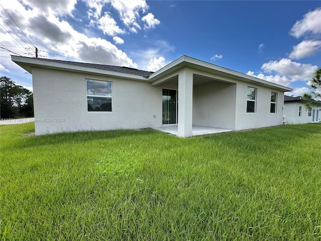 back of property featuring a patio area and a lawn