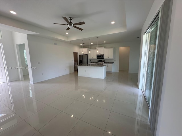 unfurnished living room featuring ceiling fan, a raised ceiling, and light tile patterned floors