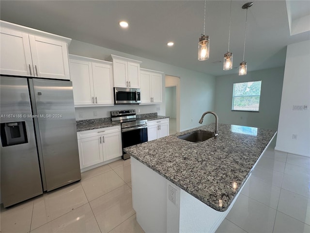 kitchen with appliances with stainless steel finishes, white cabinets, sink, and an island with sink