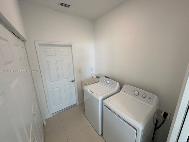 laundry room featuring light tile patterned floors, washing machine and dryer, and sink