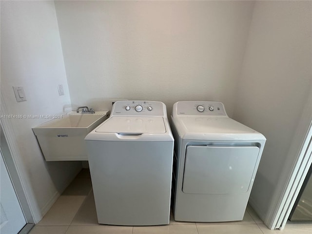 washroom featuring light tile patterned flooring, washing machine and dryer, and sink