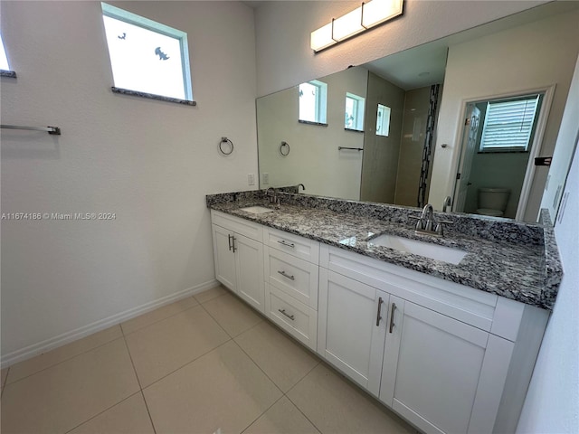 bathroom with toilet, vanity, and tile patterned floors