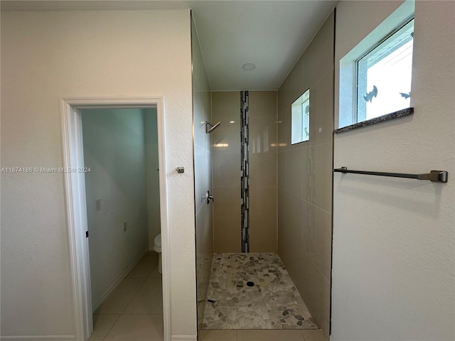 bathroom with tiled shower, toilet, and tile patterned floors