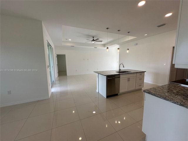 kitchen featuring a raised ceiling, hanging light fixtures, white cabinetry, stainless steel dishwasher, and a center island with sink