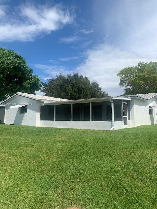 back of property with a yard and a sunroom