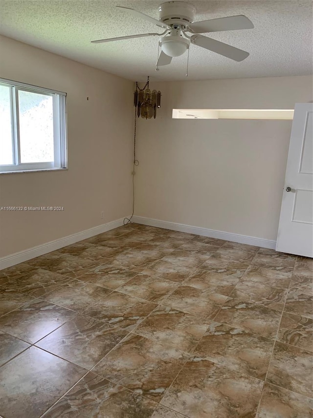 empty room with a textured ceiling and ceiling fan