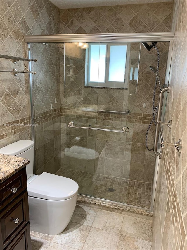 bathroom featuring a shower with door, vanity, and toilet