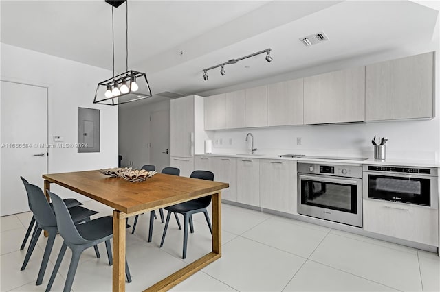 kitchen with light tile patterned flooring, stainless steel oven, hanging light fixtures, and sink