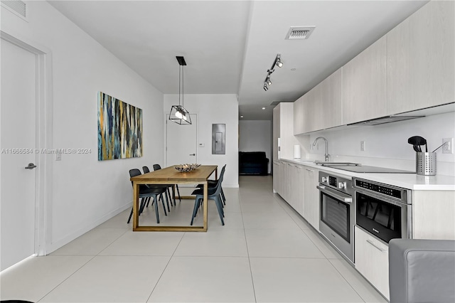 kitchen with black electric cooktop, hanging light fixtures, oven, and sink