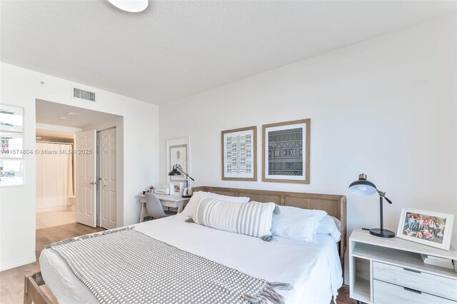 bedroom featuring ensuite bathroom and light hardwood / wood-style flooring