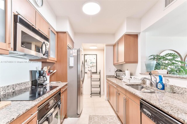 kitchen with sink, light stone counters, light tile patterned floors, and appliances with stainless steel finishes