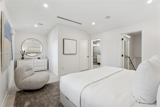 bedroom with vaulted ceiling, light hardwood / wood-style flooring, and ensuite bathroom