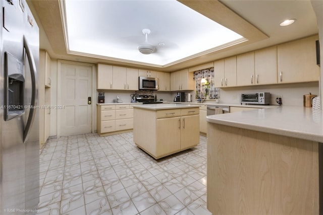 kitchen featuring kitchen peninsula, cream cabinets, a kitchen island, a raised ceiling, and stainless steel appliances