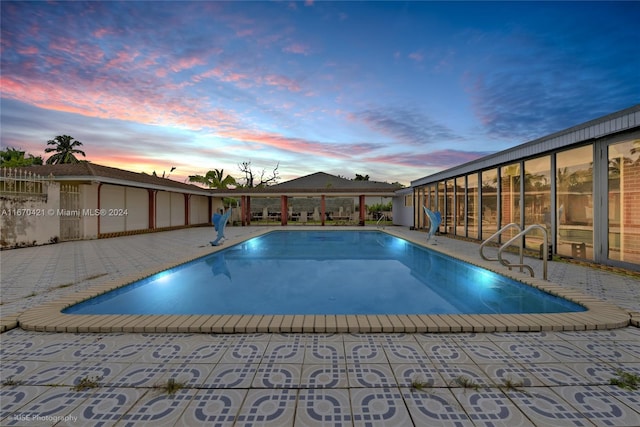 pool at dusk featuring a patio