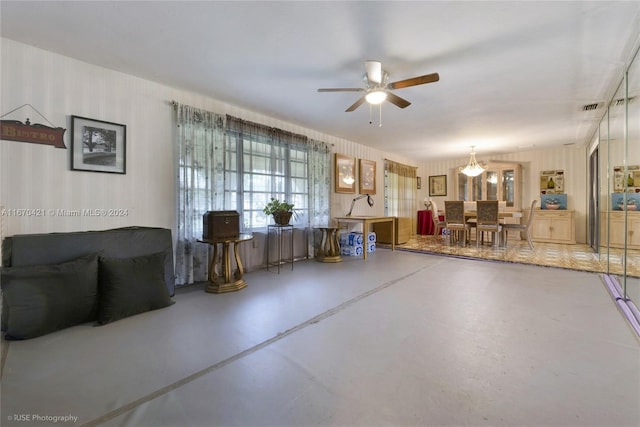 living room featuring concrete flooring and ceiling fan with notable chandelier