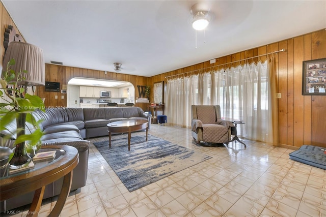 living room featuring ceiling fan and wood walls