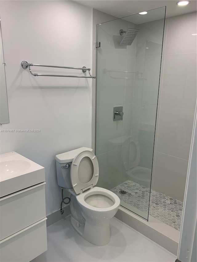 bathroom featuring vanity, a shower with shower door, and toilet