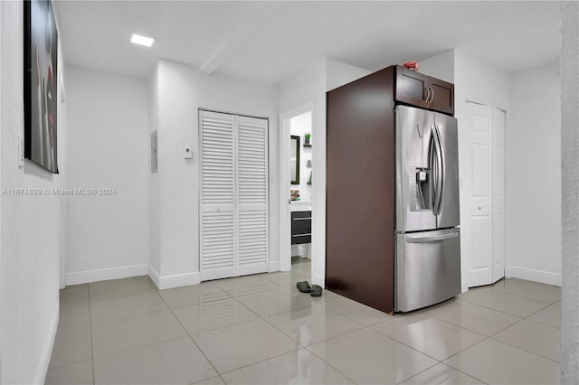 kitchen featuring dark brown cabinetry, stainless steel refrigerator with ice dispenser, and light tile patterned floors